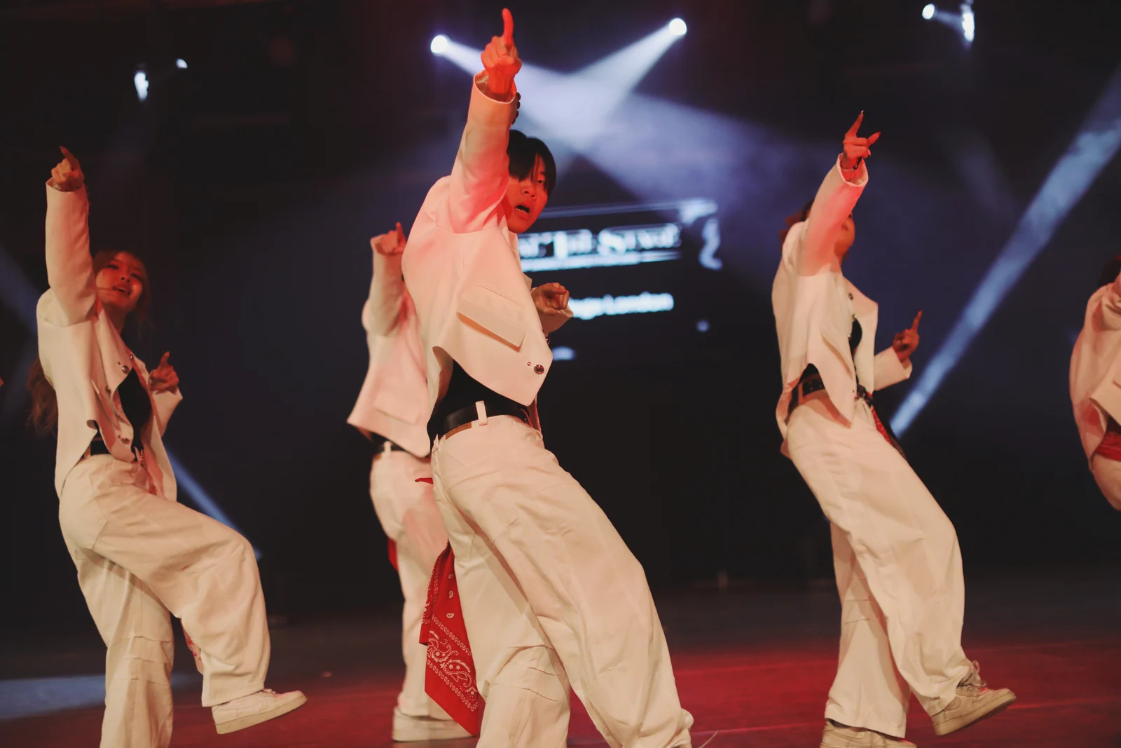 Dancers dressed in white pointing to the sky whilst performing on stage